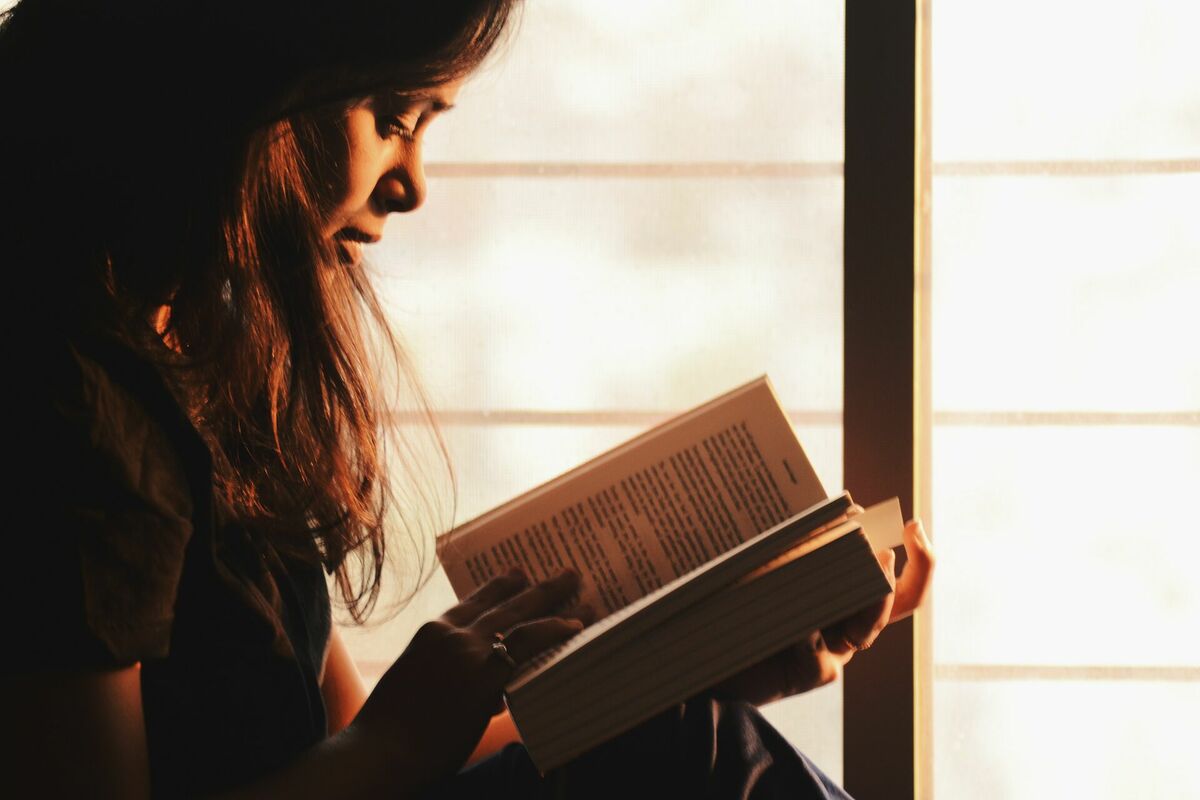Redzes slodze tuvumā, Photo by Rahul Shah: https://www.pexels.com/photo/woman-reading-a-book-beside-the-window-1031588/