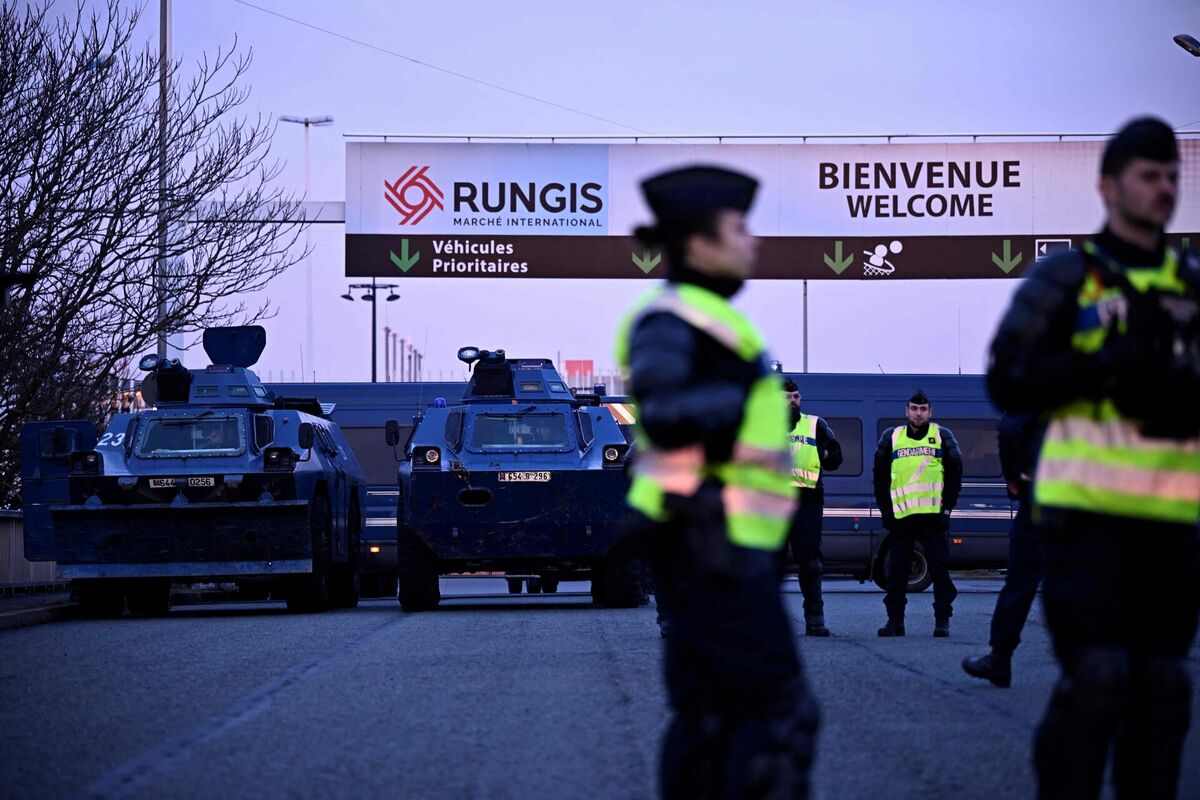 Bruņumašīnas un Francijas žandarmi stāv sardzē pie ieejas Rungī pārtikas vairumtirdzniecības tirgū Parīzes dienvidos, 28. janvārī. Lauksaimnieki no Lot-et-Garonne reģiona, kas ir viens no protestu kustības karstajiem punktiem, jau ir paziņojuši par savu nodomu bloķēt milzīgo Rungis pārtikas vairumtirdzniecības tirgu uz dienvidiem no galvaspilsētas. Foto: ULIEN DE ROSA / AFP