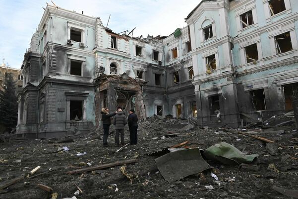 Vietējie iedzīvotāji sarunājas pie stipri cietušās ēkas Harkivā 2024. gada 24. janvārī. Foto: SERGEY BOBOK / AFP