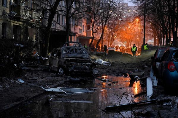 Izpostītas automašīnas pie bojātas dzīvojamās ēkas pēc raķetes trieciena Kijivā, 13. decembris. Foto: SERGEI CHUZAVKOV / AFP