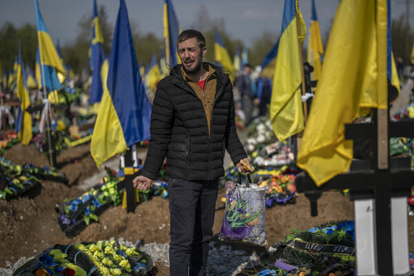 Vīrietis raud pie sava drauga, Ukrainas karavīra, kapa Krivijrihas kapsētā, 2023. gada 23. aprīlī. Foto: AP Photo/Bernat Armangue