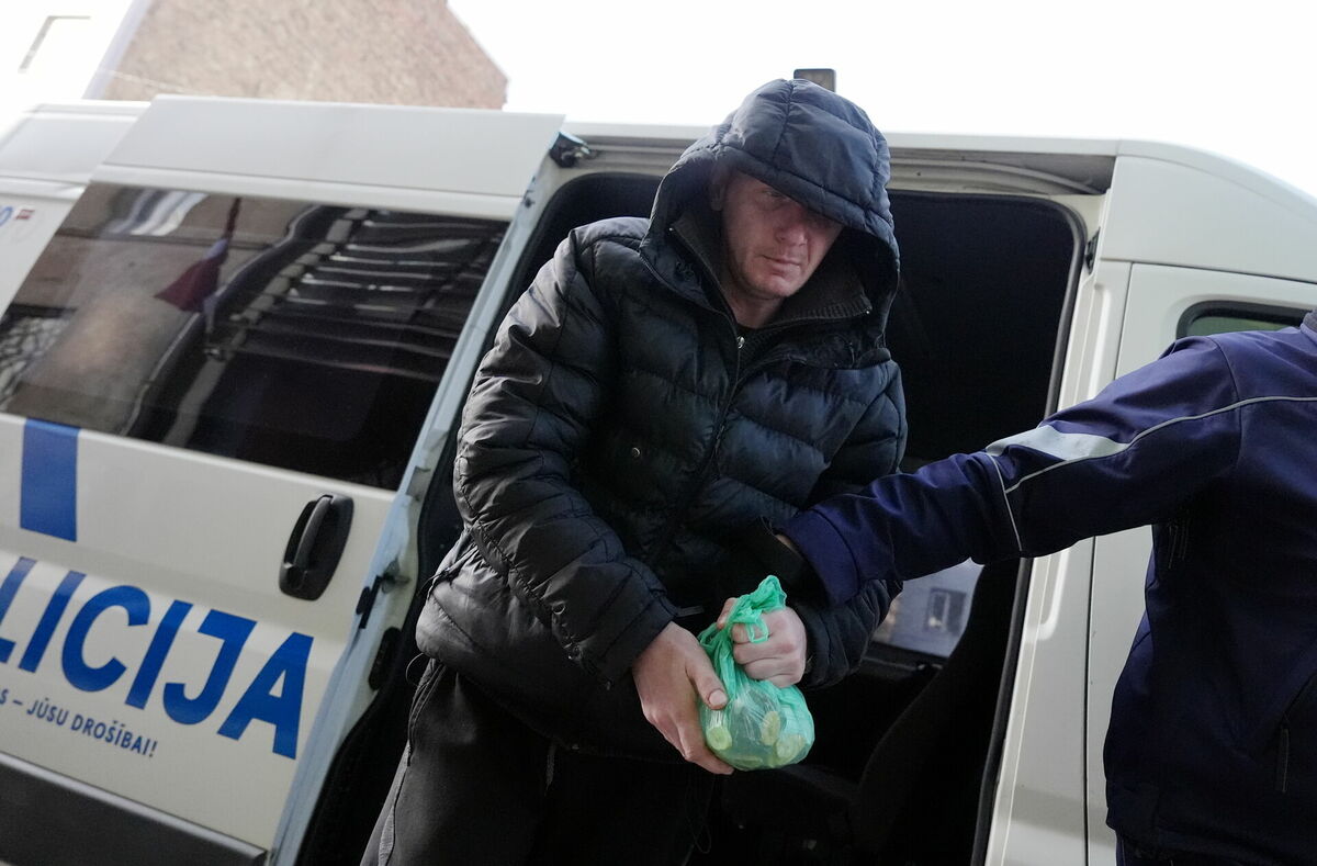 Okupācijas muzeja dedzinātāšanas lietā viens no aizturētajiem vīrietiešiem tiek konvojēts uz tiesas sēdi Rīgas pilsētas Vidzemes priekšpilsētas tiesā, kur lems par apcietinājuma piemērošanu. Foto: Edijs Pālens/LETA