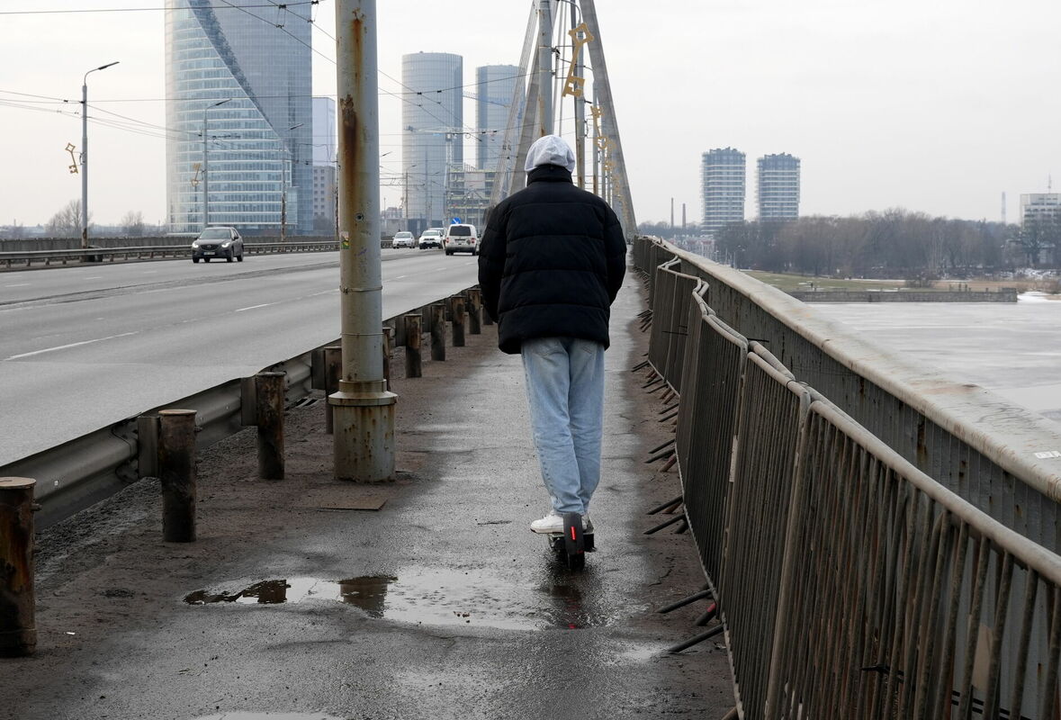 Cilvēks uz elektriskā skrejriteņa šķērsojot Vanšu tiltu. Foto: Evija Trifanova/LETA