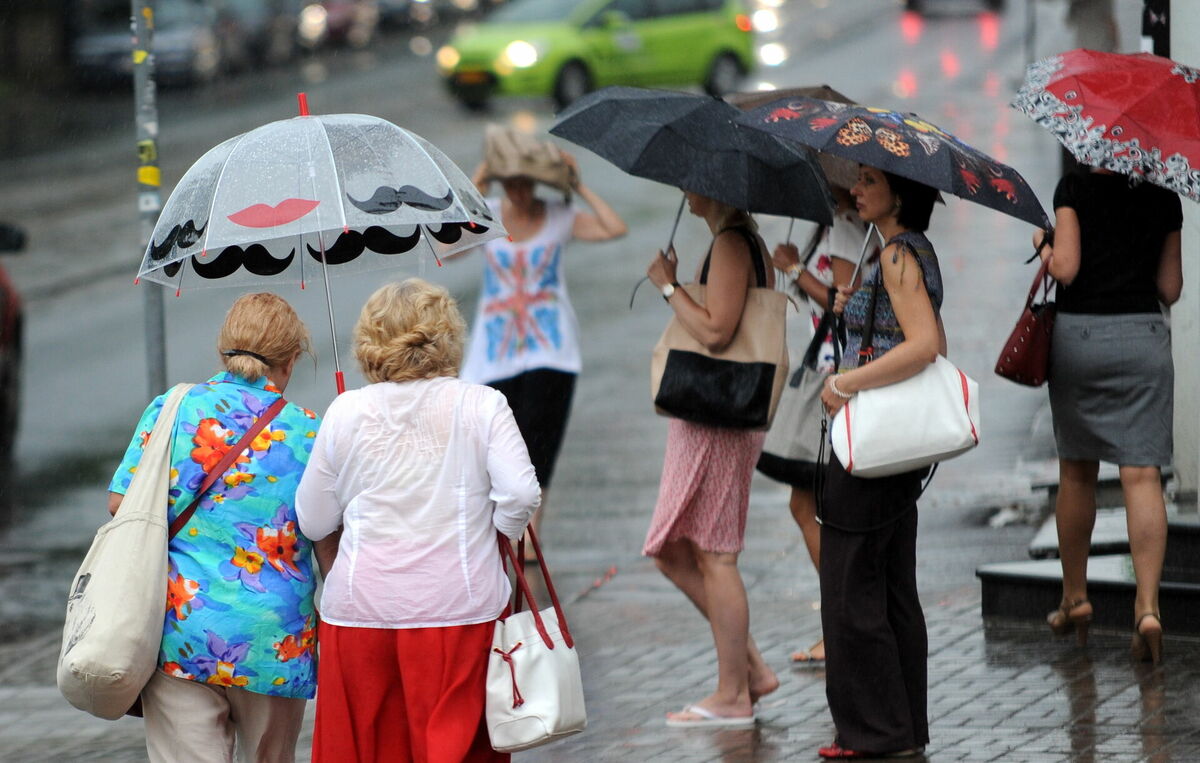 Cilvēki lietus laikā. Foto: Edijs Pālens/LETA