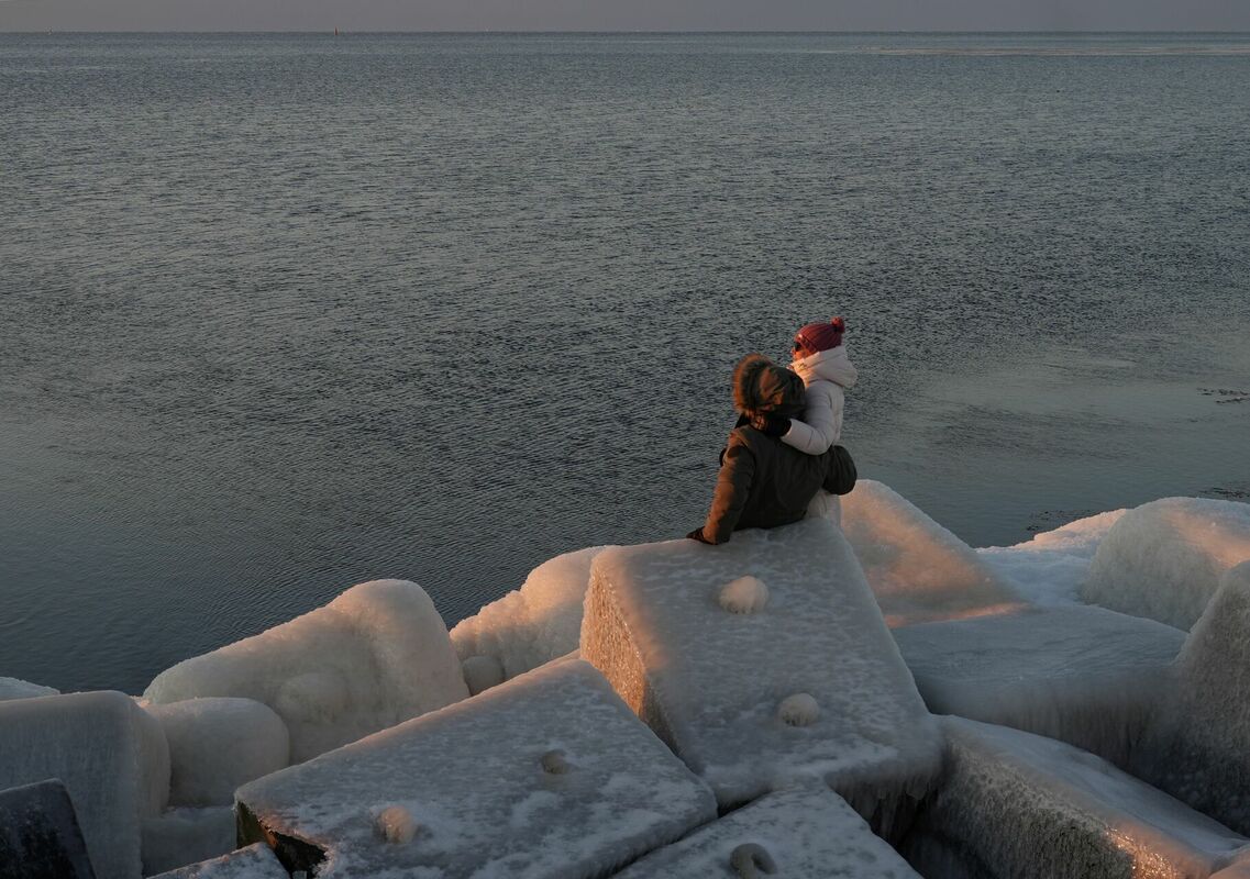 Cilvēki vēro saulrietu uz Mangaļsalas mola. Foto: LETA